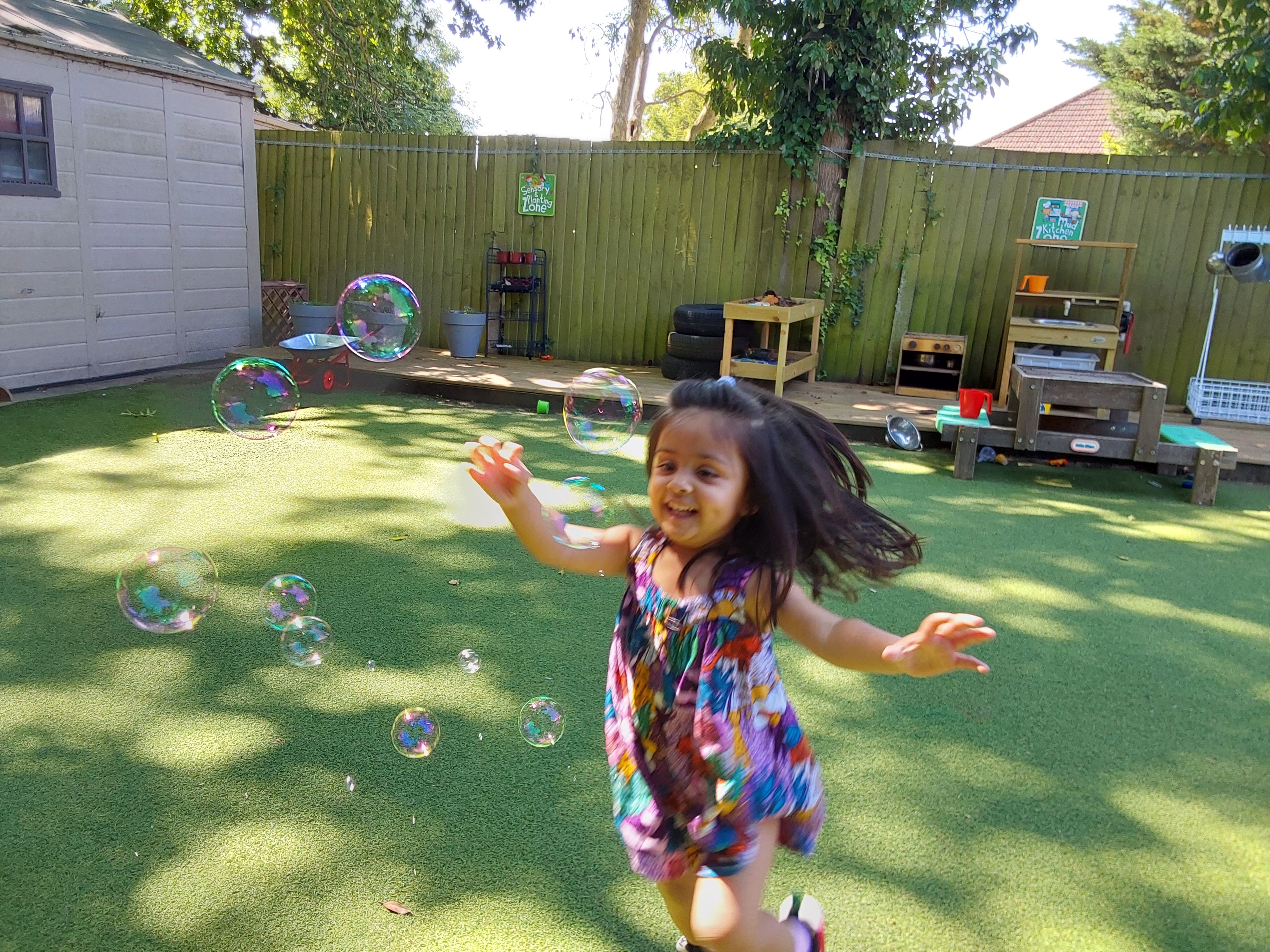 A joyful child chasing bubbles in the Apple Tree nursery garden